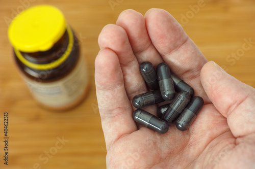 Activated vegetable charcoal capsules in a hand