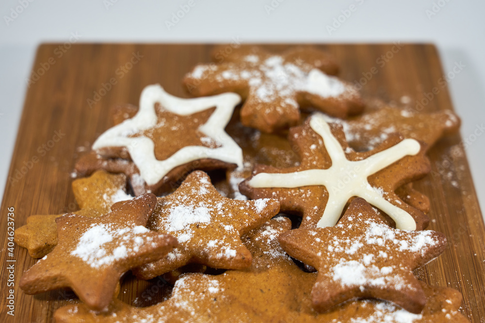 Ginger biscuits with sugar powder on a wooden board on a white background. Ginger biscuits with sugar powder on a wooden board on a white background.