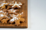 Ginger biscuits with sugar powder on a wooden board on a white background.