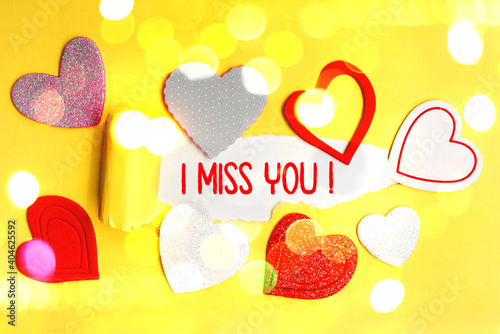 English text I Miss You written in red letters on a yellow card with love hearts. photo