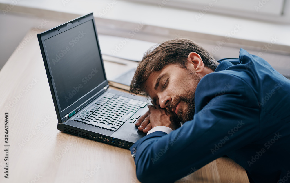 Man in a suit at a working table in front of a laptop office tired Man in a suit at a working table in front of a laptop office tired