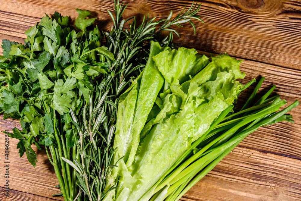 Lettuce rosemary and parsley on a wooden table. Vegan food. Top view Lettuce rosemary and parsley on a wooden table. Vegan food. Top view