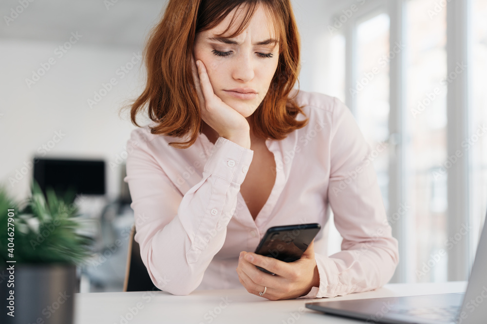 Glum young businesswoman reading a phone message Glum young businesswoman reading a phone message