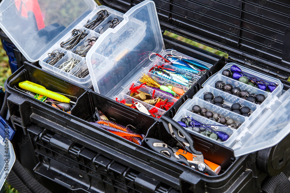 A large fisherman's tackle box fully stocked with lures and gear for  fishing.fishing lures and accessories in the box background. Stock Photo