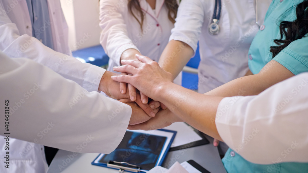 Close-Up of Medical Workers Stack Hands on the Table Together for Support at Work. Team of Doctors at Modern Hospital. Team spirit at modern at Clinic. Close-Up of Medical Workers Stack Hands on the Table Together for Support at Work. Team of Doctors at Modern Hospital. Team spirit at modern at Clinic.