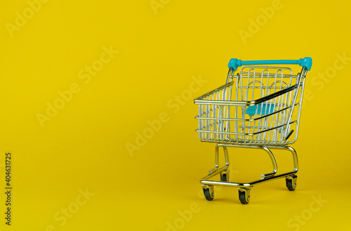 Empty shopping cart isolated on yellow background with empty space for text