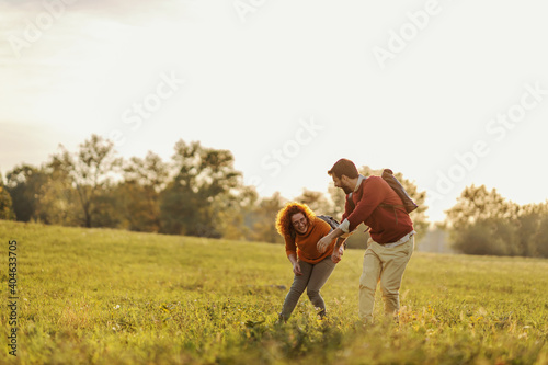 Young happy couple in love holding hands and running on meadow. It's a beautiful sunny autumn day. Freedom.
