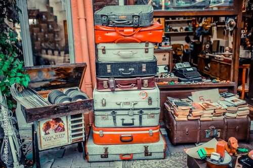 Racked suitcases in front of antique shop. colorful old suitcases. old plaques and books