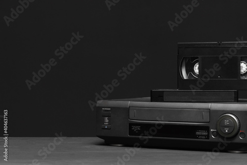 Valokuva Video recorder and video tapes on the table on the black background