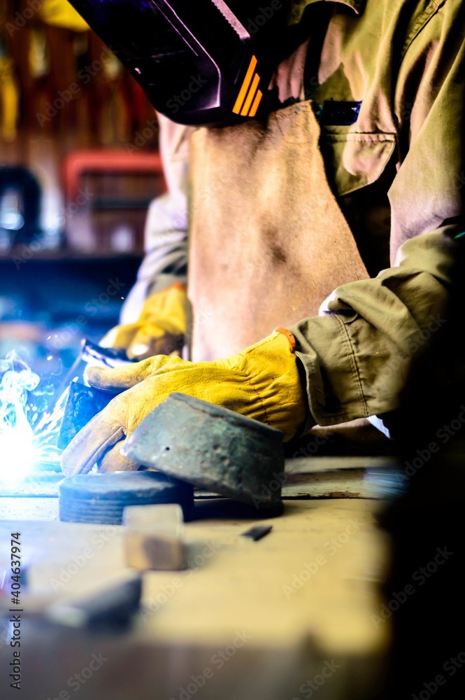 Elderly man welding in a workshop surrounded by tools