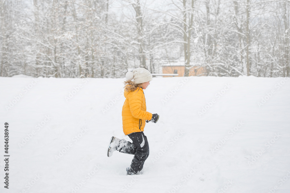 Young happy girl is running in snow in winter. Outdoor activity and fun in winter nature.