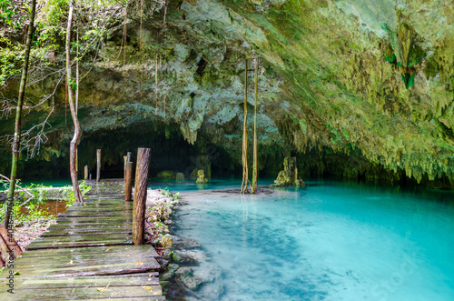 wooden pathway in cenote with stalactites and crystal clear fresh water near Tulum - Riviera Maya, Tulum, Yucatan, Mexico