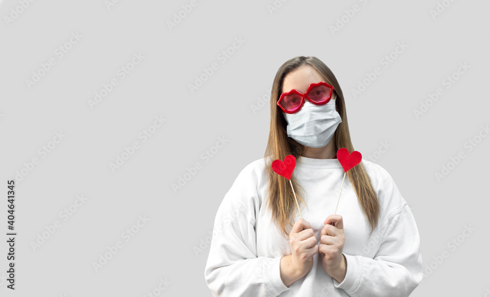 Portrait of woman in funny glasses and medical protective wearing mask holding in hands red hearts. concept of valentines day during pandemic period, valentine