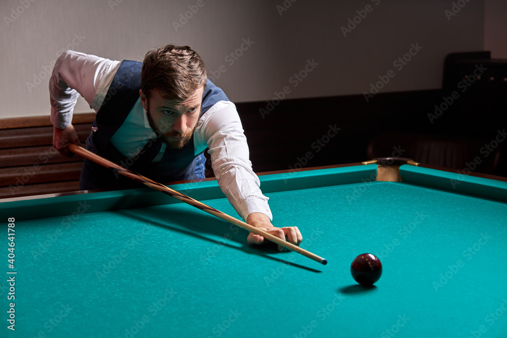 Fototapeta premium man leaning over the table while playing snooker, he is concentrated on game, having leisure time