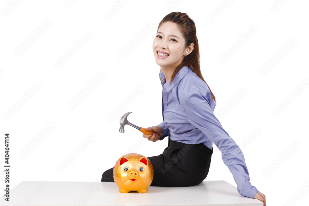 Businesswoman using hammer to smash open a piggybank Businesswoman using hammer to smash open a piggybank