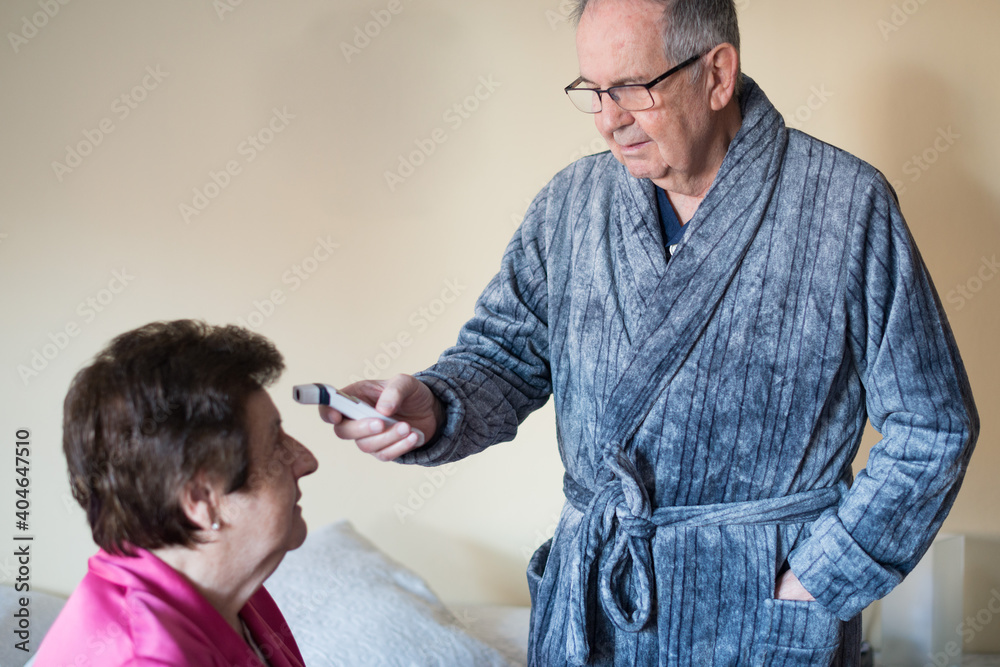 Senior adult couple at home during temperature check for Covid-19 with a digital thermometer Senior adult couple at home during temperature check for Covid-19 with a digital thermometer