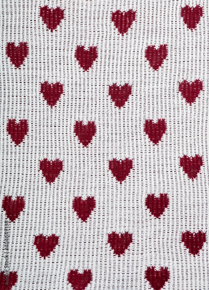 Knitted white background with a red pattern in the shape of heart. Knitted white background with a red pattern in the shape of heart.
