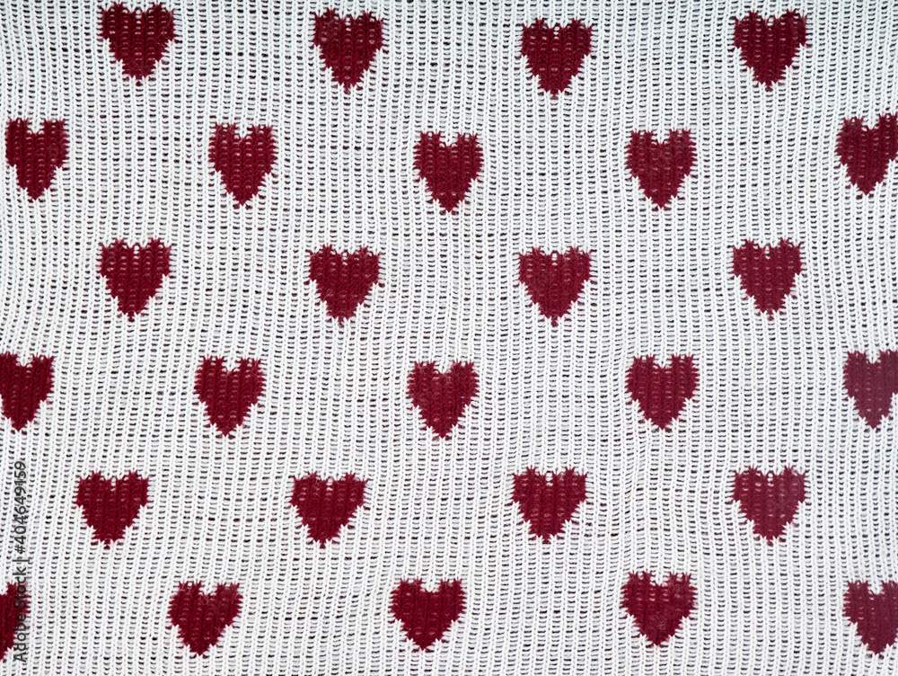 Knitted white background with a red pattern in the shape of heart. Knitted white background with a red pattern in the shape of heart.
