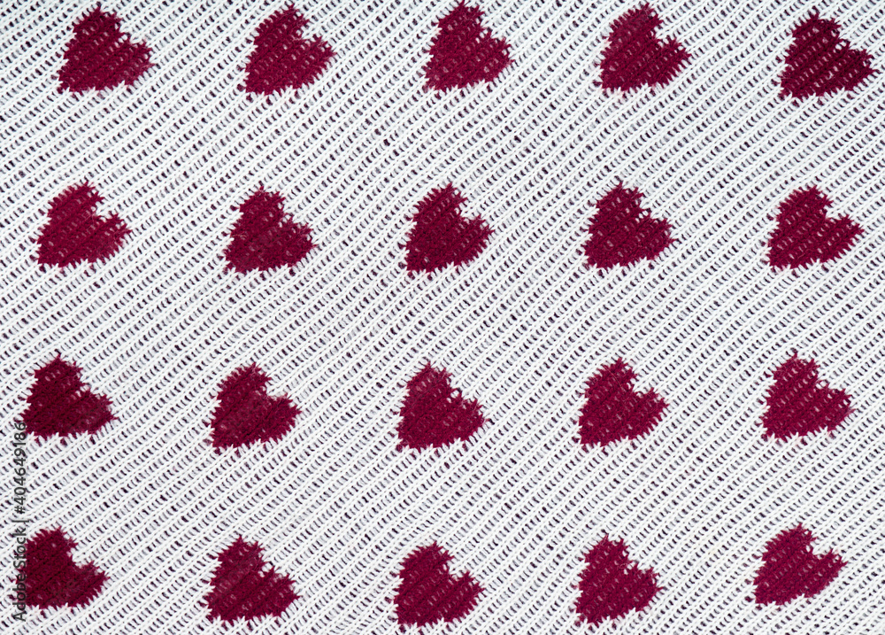 Knitted white background with a red pattern in the shape of heart. Knitted white background with a red pattern in the shape of heart.