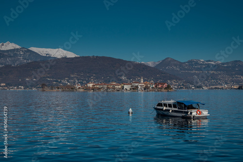 Wide panorama of Isola Superiore on lago Maggiora in italy on a beautiful sunny winter day. Majestic mountains with snow visible in the background.