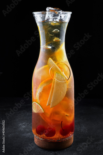 Sangria in a transparent jug with ice, on a black background