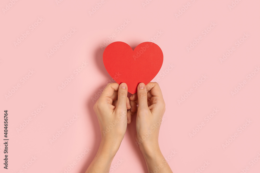Top view of woman hands holding blank paper greeting or invitation card over pink pastel background with heart shape. Christmas, Valentine, New Year, winter holidays concept Top view of woman hands holding blank paper greeting or invitation card over pink pastel background with heart shape. Christmas, Valentine, New Year, winter holidays concept