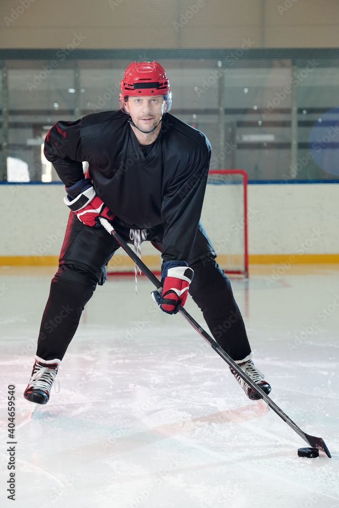 Φωτογραφία Mature hockey player in protective helmet and gloves moving down ice rink