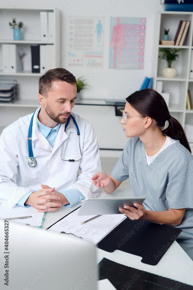 Two young confident clinicians discussing medical document and consulting