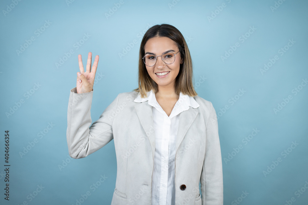 Young business woman over isolated blue background showing and pointing up with fingers number three while smiling confident and happy Young business woman over isolated blue background showing and pointing up with fingers number three while smiling confident and happy