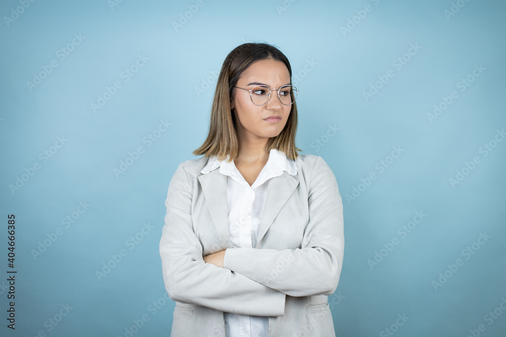 Young business woman over isolated blue background thinking looking tired and bored with crossed arms Young business woman over isolated blue background thinking looking tired and bored with crossed arms