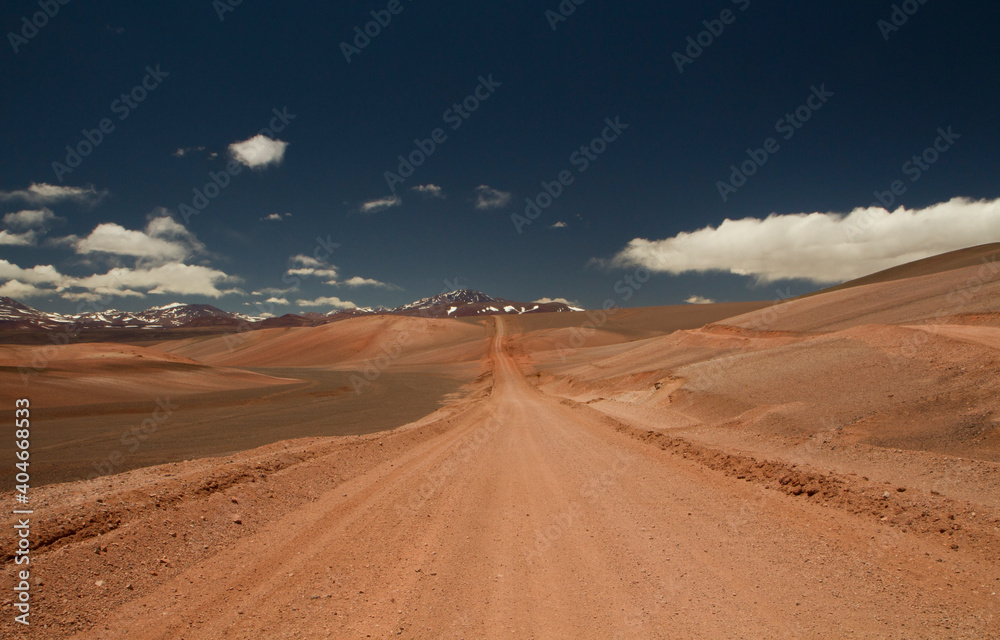 The dirt road high in the Andes mountains. Traveling along the route across the arid desert dunes and mountain range. The sand and death valley under a deep blue sky in La Rioja, Argentina.