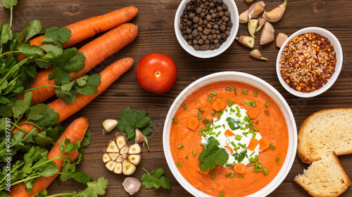 Natural carrot soup with herbs for breakfast. On a wooden table.