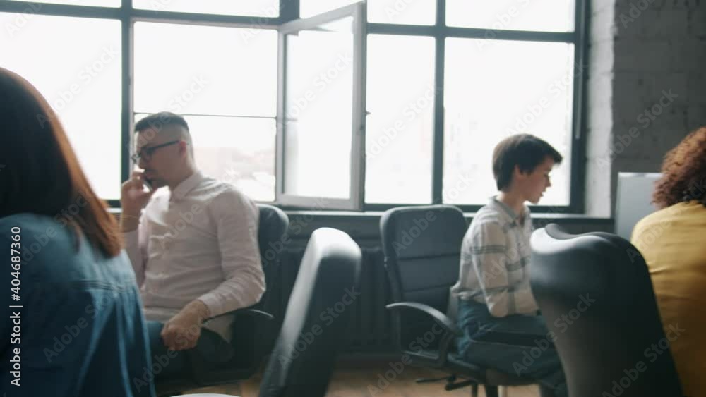Dolly shot of multi-ethnic group of businesspeople working in open plan office sitting at desks using computers concentrated on business. People and workplace concept.