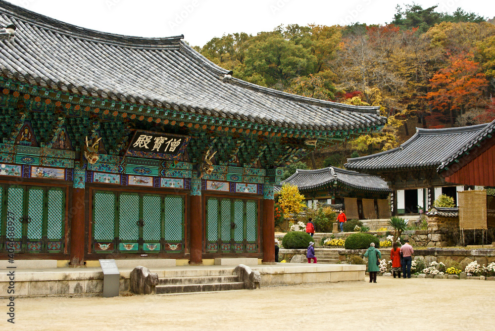 In Jogyesan Provincial Park, South Korea, visitors explore Seonamsa's weathered-wood temple buildings amid brilliant fall foliage.