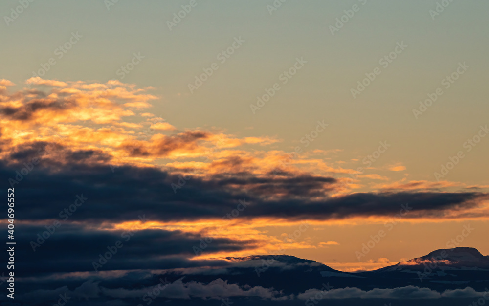 a thick layer of clouds with a glowing orange edge above the horizon near the golden hour over the coast