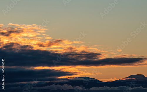 a thick layer of clouds with a glowing orange edge above the horizon near the golden hour over the coast © Yi