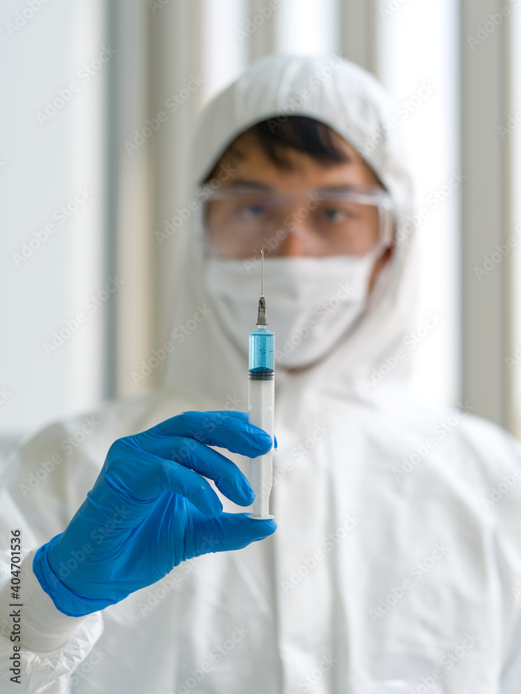 A syringe containing a blue anti-virus drug in the hands of researchers. A syringe containing a blue anti-virus drug in the hands of researchers.