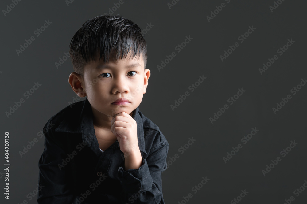 Asian boy touching his chin with thinking expression Asian boy touching his chin with thinking expression
