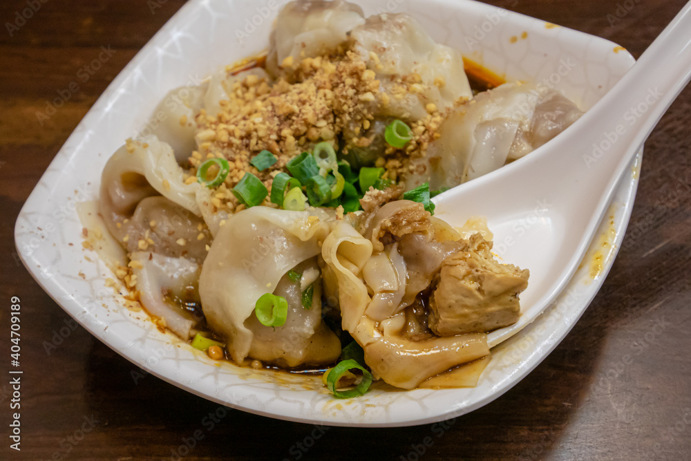 The close up of Taiwanese traditional steamed spicy stinky tofu wontons cuisine with spoon on old wooden table at food night market restaurant in Taipei, Taiwan. The close up of Taiwanese traditional steamed spicy stinky tofu wontons cuisine with spoon on old wooden table at food night market restaurant in Taipei, Taiwan.
