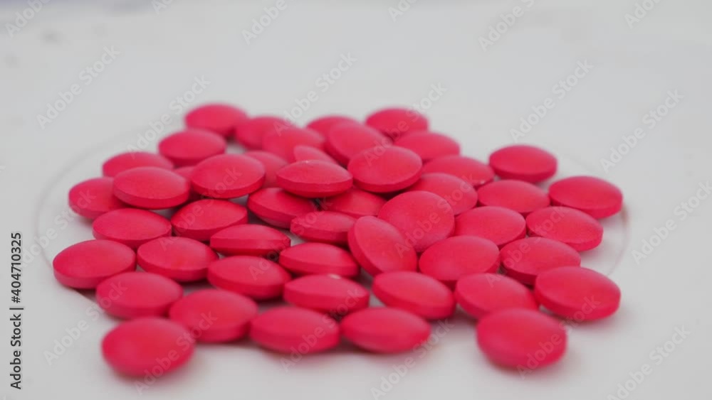 Macro rotating shot of pink tablets placed over a table Macro rotating shot of pink tablets placed over a table