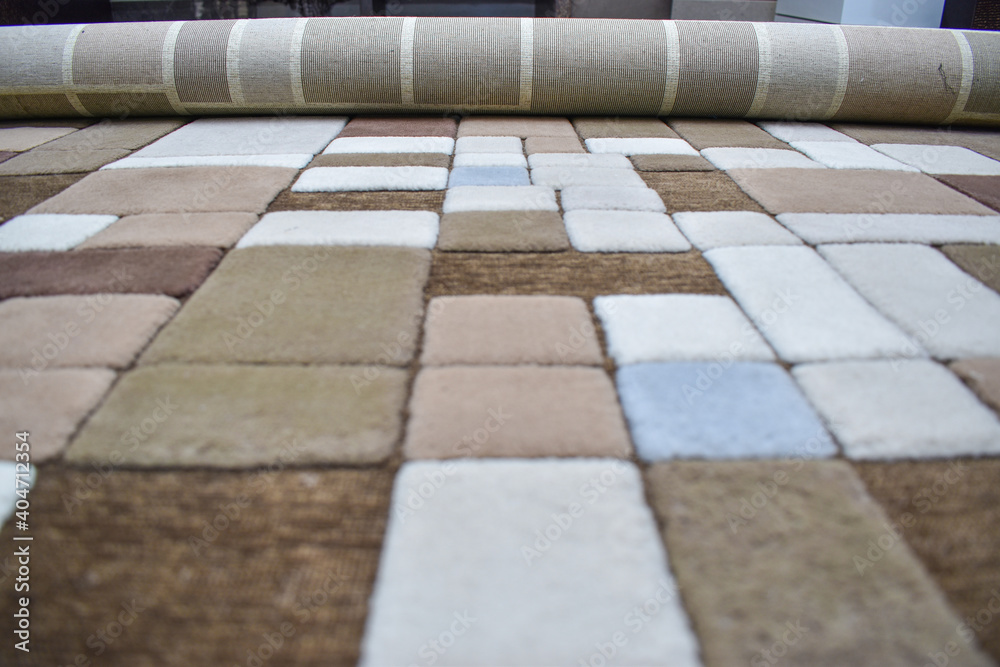 designer rolling carpet in indoors , closeup shot .Perspective shot of shades of square brown color carpet.