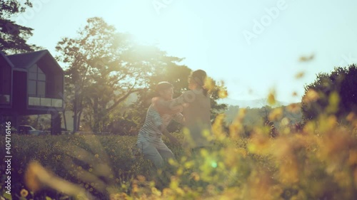 romance mement of the Asian happy romantic couple in love running hold hug together in the flower field at the sunset, hugging and looking at each other. valentine concept photo