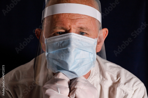 A middle-aged man with face mask, faceguard and rubber gloves.