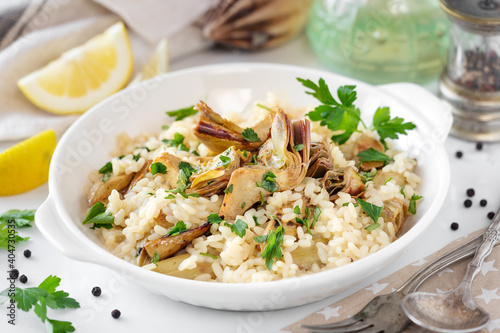 Italian risotto with artichokes and fresh parsley served on a white plate photo