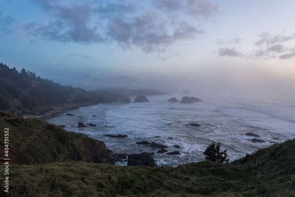 Soft colors of foggy winter sunset over Ecola State Park in Oregon