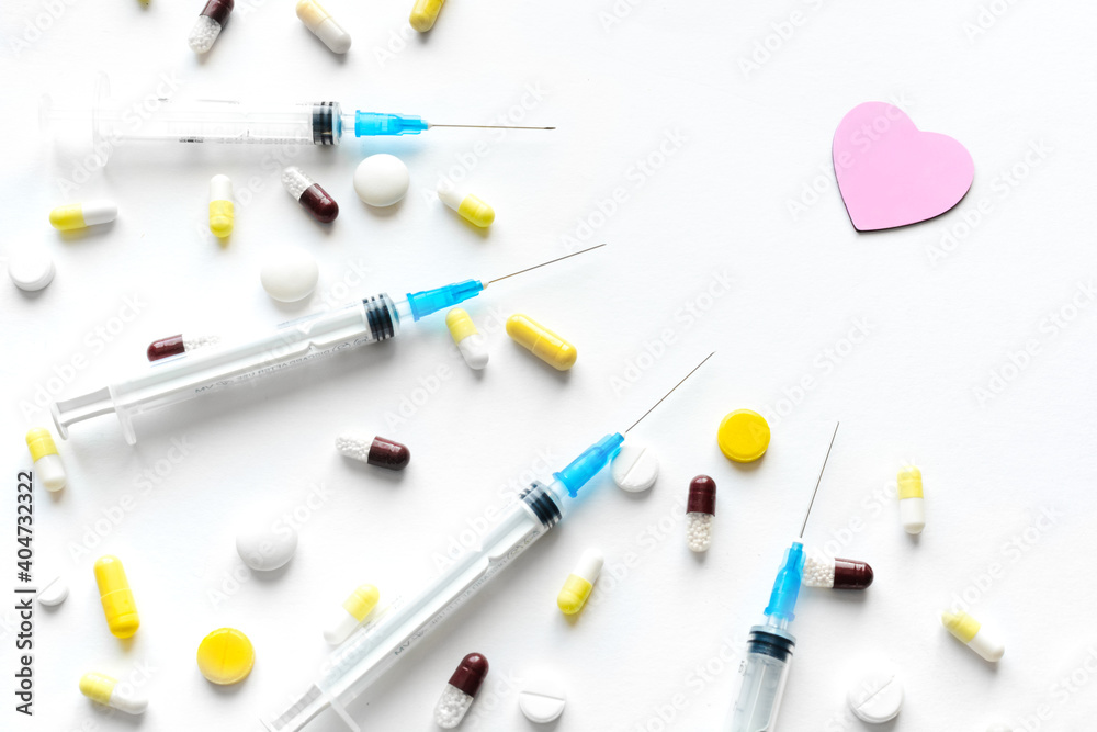 Heart treatment. Drugs harm to heart. Pink heart surrounded by many drugs, syringes and pills. Flat lay. Top view Heart treatment. Drugs harm to heart. Pink heart surrounded by many drugs, syringes and pills. Flat lay. Top view