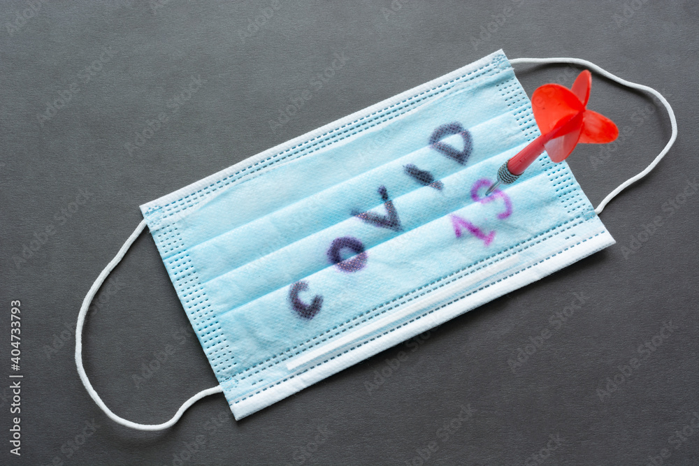 Winning Covid-19, coronavirus concept. Dart in medical face protective mask with inscription Winning Covid-19, coronavirus concept. Dart in medical face protective mask with inscription