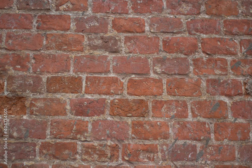 Brick texture from old stone. 18th century brick wall. Old burnt brick masonry. Shooting details close-up. Aged red clay color. Rectangular blocks laid out in rows and held together with cement. Brick texture from old stone. 18th century brick wall. Old burnt brick masonry. Shooting details close-up. Aged red clay color. Rectangular blocks laid out in rows and held together with cement.