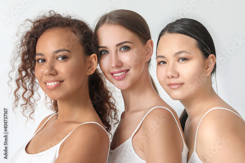 Portrait of beautiful young women with different tones of skin on light background