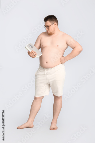 Overweight man with scales ...